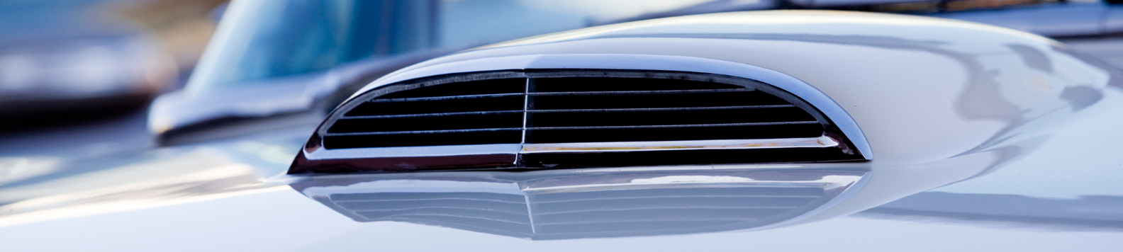 Een luchthapper of air intake, gemonteerd in de motorkap van een zilvergrijze auto