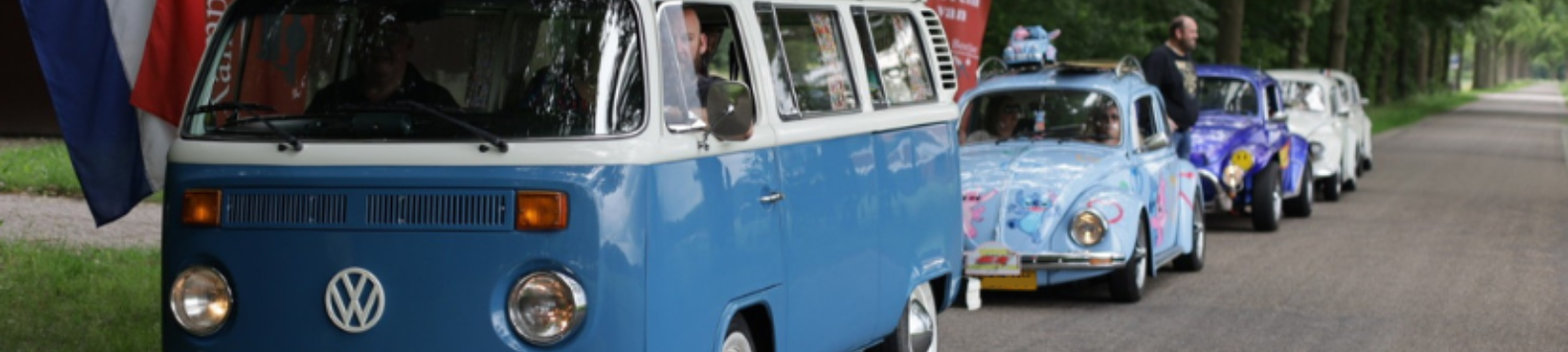 Een rij met verschillende oldtimers achter elkaar langs de weg