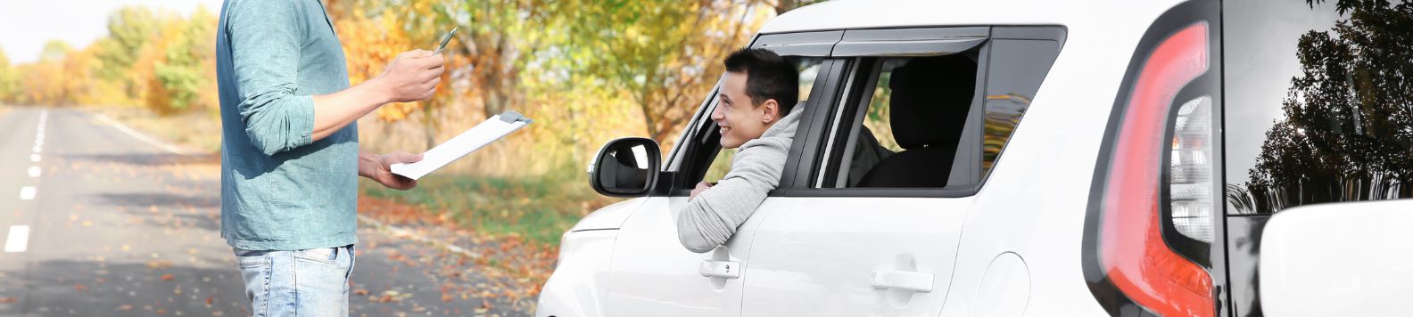 Een meneer met een klembord houdt een jongeman in een witte auto staande.